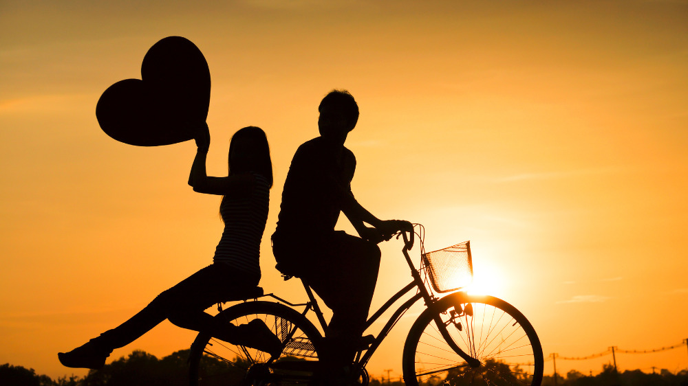 夕日をバックに自転車を二ケツする男女